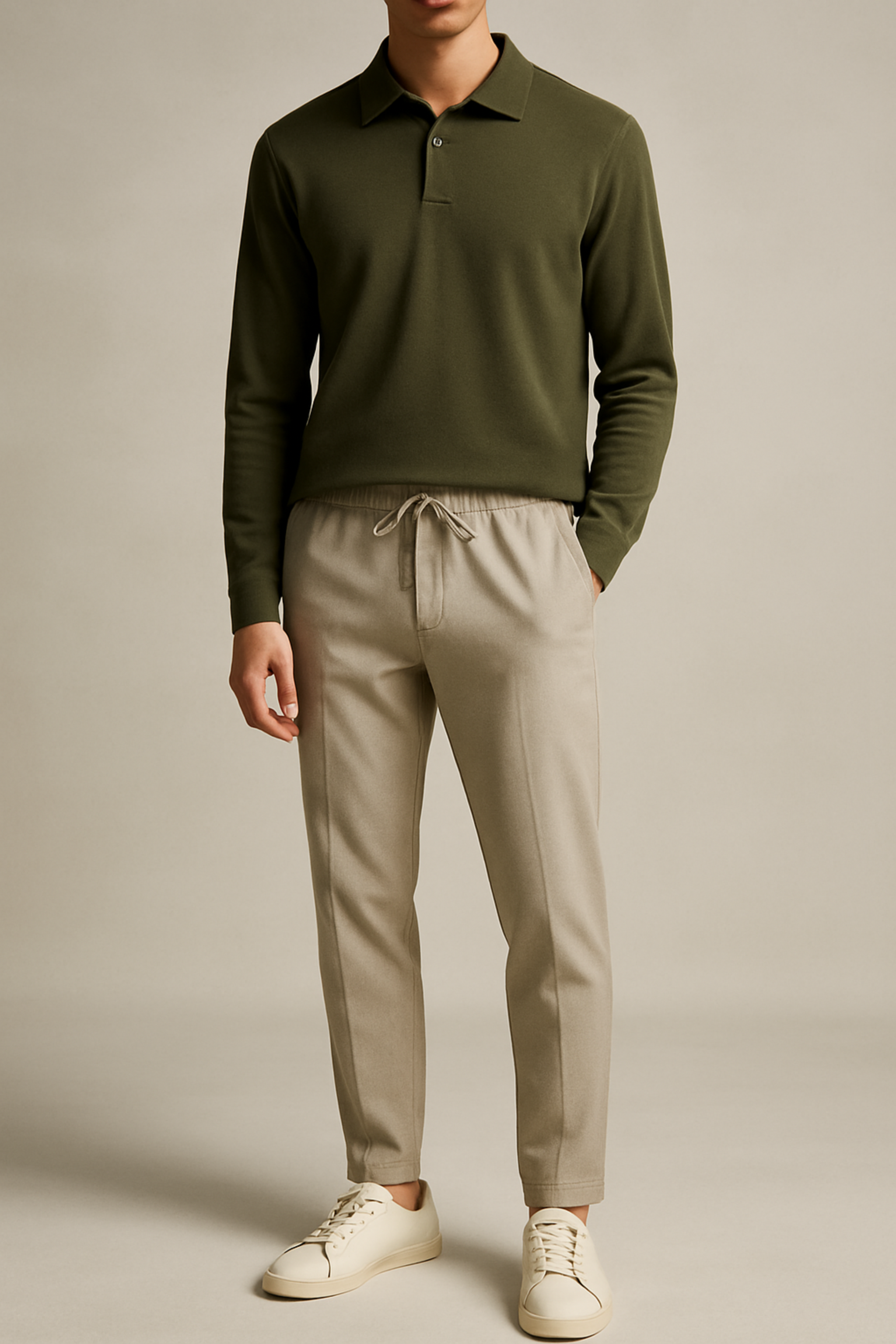 Person wearing a green long-sleeve shirt and beige pants on a plain background